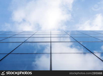 detail of modern corporate office building with glass and steel reflecting blue sky and clouds