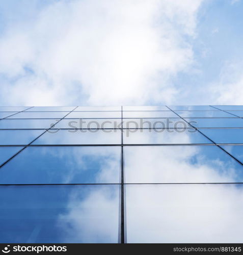 detail of modern corporate office building with glass and steel reflecting blue sky and clouds