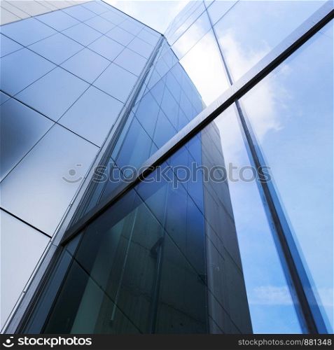 detail of modern corporate office building with glass and steel reflecting blue sky and clouds