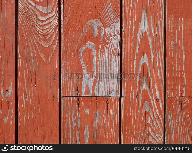Detail of old wooden nails fastened fence with shelled red paint in sunlight . Fragment of wooden fence with shelled paint. Fragment of wooden fence with shelled paint