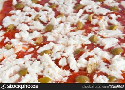 detail of raw pizza with tomato mozzarella and olives