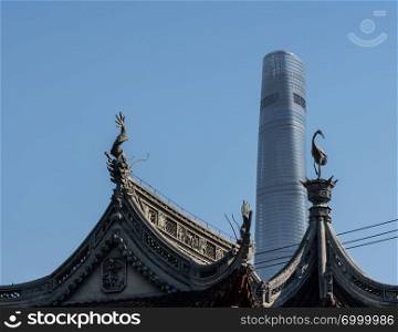 Detail of roof carvings with modern tower block in Yuyuan Garden in  the old city of Shanghai. Detail of roofs with tower block in Yu Garden in Shanghai