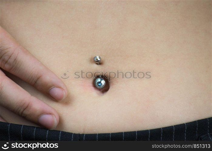 Detail of the belly of a young woman, wearing a navel piercing isolated. Detail of the belly of a young woman, wearing a navel piercing
