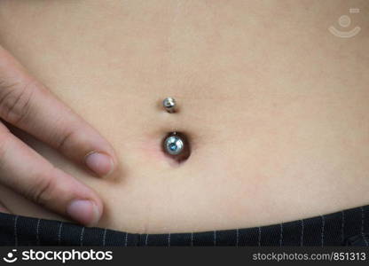 Detail of the belly of a young woman, wearing a navel piercing isolated. Detail of the belly of a young woman, wearing a navel piercing