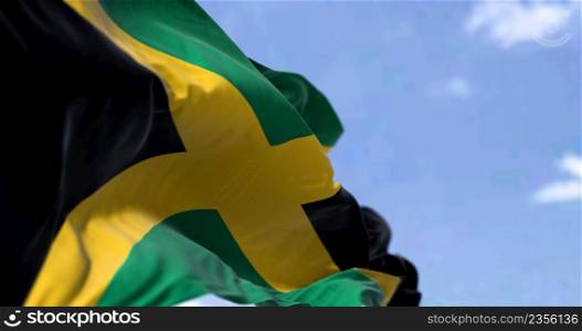 Detail of the national flag of Jamaica waving in the wind on a clear day. Jamaica is an island country situated in the Caribbean Sea. Selective focus.