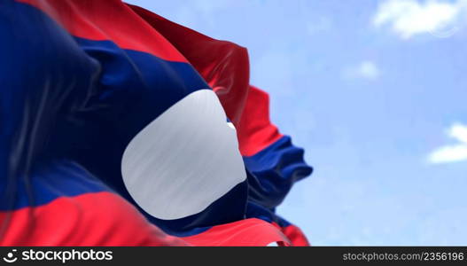 Detail of the national flag of Laos waving in the wind on a clear day. Laos is a socialist state and the only landlocked country in Southeast Asia. Selective focus.