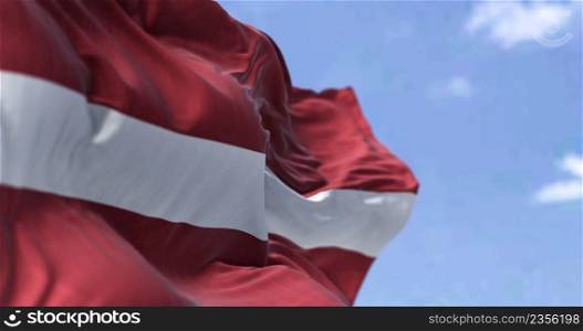 Detail of the national flag of Latvia waving in the wind on a clear day. Latvia is a country in the Baltic region of Northern Europe. Selective focus.