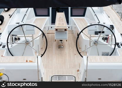 Detail of the steering wheels and symmetry in the deck of a luxury sail yatch.