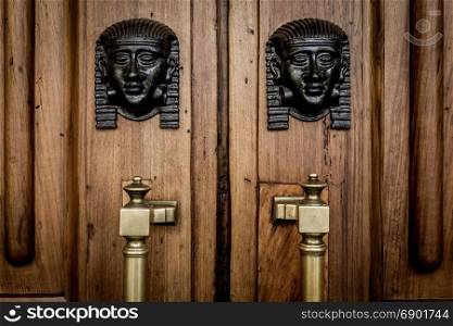 Detail of two bronze Sphinx heads on an old wooden door - around 100 years old, Italian palace in North Italy