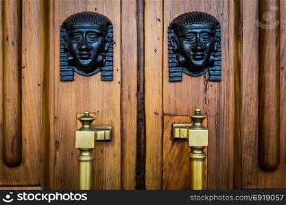 Detail of two bronze Sphinx heads on an old wooden door - around 100 years old, Italian palace in North Italy