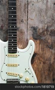Detail of White Electric Guitar on a wood background.