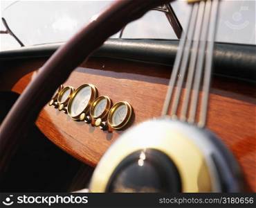 Detail of wooden boat with steering wheel and dashboard.