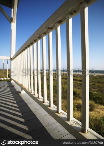 Detail of wooden railing on porch overlooking beach at Bald Head Island, North Carolina.