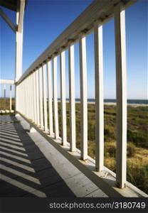 Detail of wooden railing on porch overlooking beach at Bald Head Island, North Carolina.