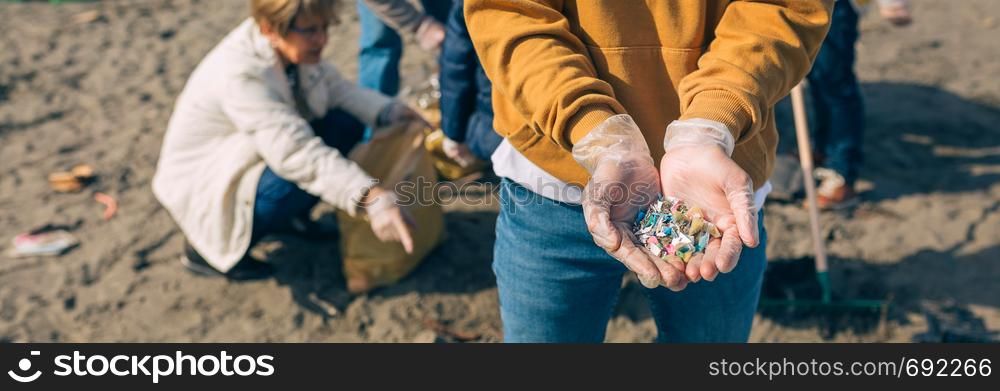 Detail of young man hands showing microplastics on the beach. Hands with microplastics on the beach