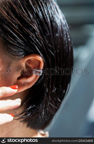Detail of young woman wearing beautiful silver earring. Women accessories. Selective focus.