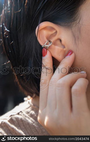 Detail of young woman wearing beautiful silver earring. Women accessories. Selective focus.