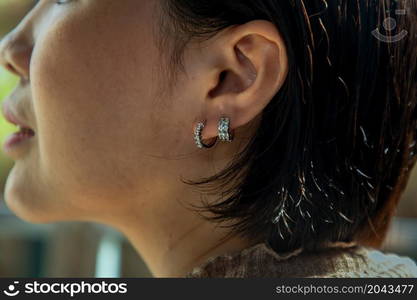 Detail of young woman wearing beautiful silver earring. Women accessories. Selective focus.