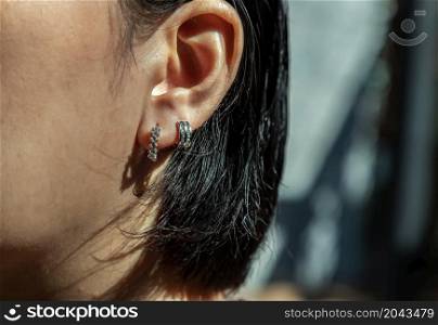 Detail of young woman wearing beautiful silver earring. Women accessories. Selective focus.
