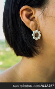 Detail of young woman wearing beautiful white pearl earring. Women accessories. Selective focus.