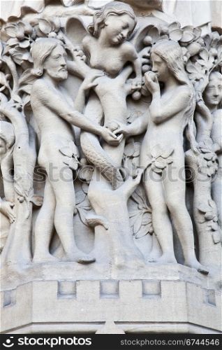 Detail on Notre Dame de Paris Cathedral fachade: Adame, Eve and the forbidden apple