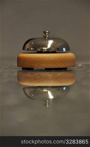 Detail shot of a service bell located on a hotel reception desk with great reflection on marble counter