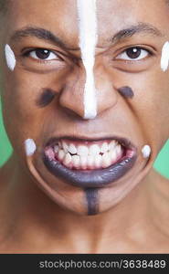 Detail shot of aggressive mixed race man with painted face clenching teeth