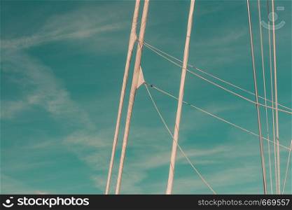 Detailed closeup of mast rigging top on sail boat during cruise, shot on blue sky. Marine objects concept.. Detailed closeup of mast rigging top on sail boat
