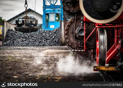 Details and different images of locomotives, marshalling yard, wagons, carriages and train stations in an old industrial heritage museum in the netherlands at Beekbergen. Steaming steam train or locomotive is waiting for coal loading by a vintage crane, industrial details and craftsmanship along the rail way and train station