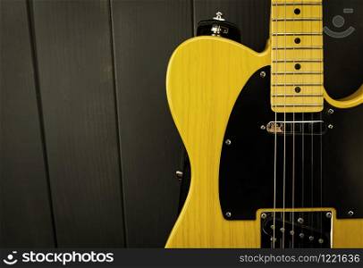 Details of a classic electric guitar in yellow and black, with its frets, strings, neck and microphone
