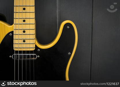 Details of a classic electric guitar in yellow and black, with its frets, strings, neck and microphone