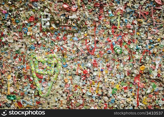 Details of a colorful wall covered in bubble gum deposited over the years in the Post Alley section of the Pike Place Market in Seattle show off a gross and disgusting landmark in Seattle.