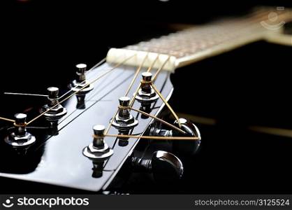 Details of acoustic black guitar. neck, nut, frets, strings.