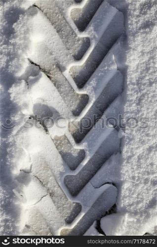 details of snow-covered road in the winter, traces of cars and tracks from transport, close-up on the roadway. details of snow-covered road
