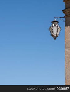 Details of the ornate wall lamp against clear blue sky with copy space. Detail of ornate lamp on side of building with blue sky