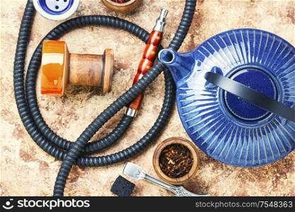 Details of tobacco hookah and teapot with tea.Egyptian smoking shisha and teakettle. Oriental hookah with kettle