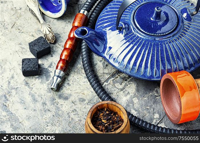 Details of tobacco hookah and teapot with tea.Egyptian smoking shisha and teakettle. Oriental hookah with kettle