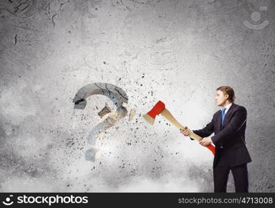 Determined businessman. Businessman breaking stone question mark with axe