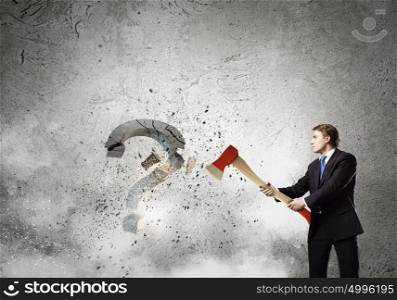 Determined businessman. Businessman breaking stone question mark with axe
