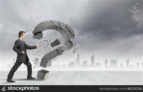 Determined businessman. Businessman breaking stone question mark with karate kick