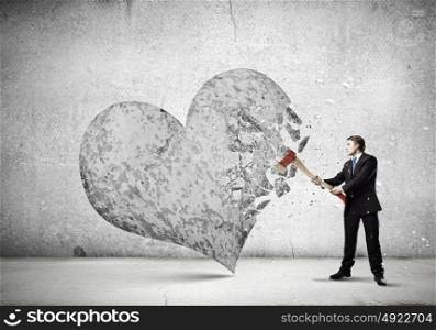Determined businessman. Young determined businessman crashing stone heart with axe