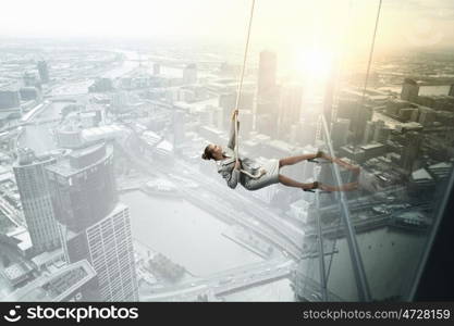 Determined businesswoman climbing building with help of rope. Getting to top