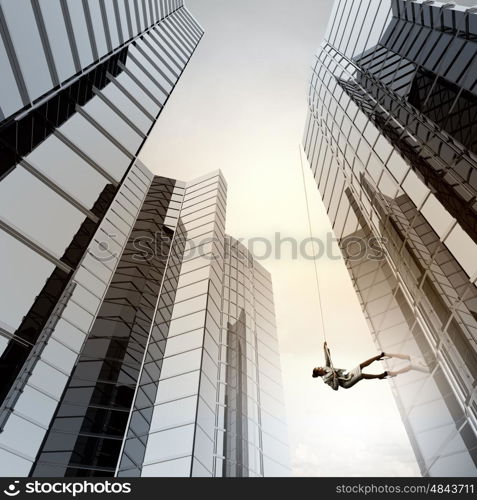 Determined businesswoman climbing building with help of rope. Getting to top