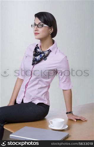 Determined businesswoman sitting on office desk