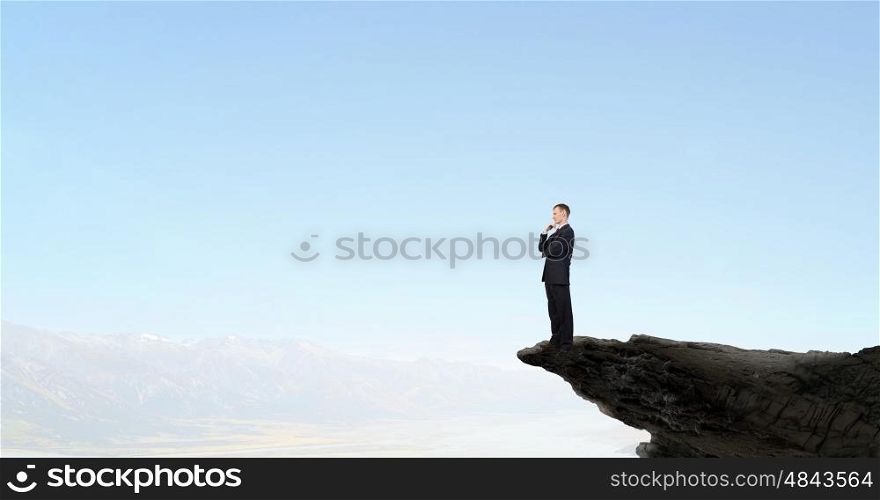 Determined in his business. Confident businessman on rock edge with his arms crossed on chest