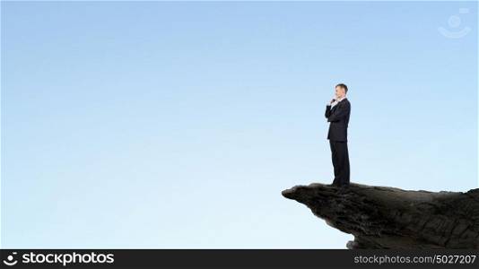 Determined in his business. Confident businessman on rock edge with his arms crossed on chest
