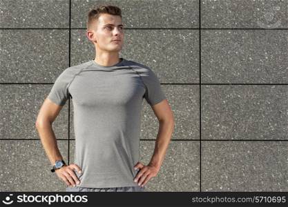 Determined jogger standing against tiled wall outdoors