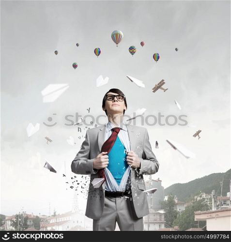 Determined super businessman . Young businessman acting like super hero and tearing his shirt off and looking up