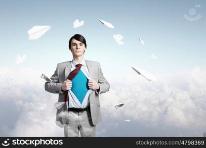 Determined super businessman . Young businessman acting like super hero and tearing his shirt off