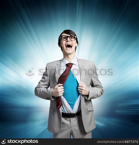 Determined super businessman . Young businessman acting like super hero and tearing his shirt off